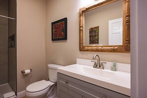 A bathroom with a toilet, a sink with a mirror, and a framed artwork on the wall. - Mesa House Dos - One block from Duval St (Key West)