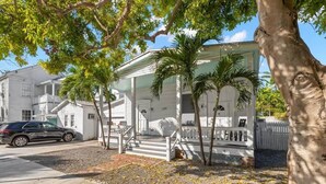 A white house with a porch, palm trees, and a car parked in front. - Mesa House Uno - One block from Duval St (Key West)