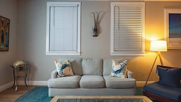 A living room with a grey sofa, two decorative pillows, a blue rug, and a floor lamp.