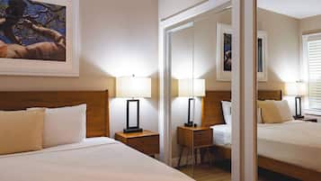 Quarto de hotel com uma cama grande, duas mesas de cabeceira com abajures, um espelho e um quadro na parede.