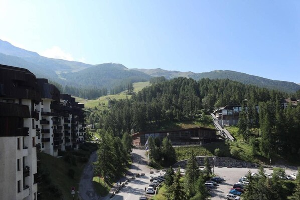 A mountainous landscape with a parking area, buildings, and a road.