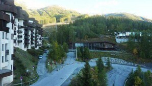 A mountainous area with a road curving through it, surrounded by greenery and buildings. - Resort center, 9th floor, balcony, tv, ski locker, 32m², Les Orres (Les Orres)
