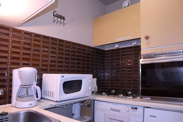 A kitchen with a coffee maker, microwave, stove, and a dishwasher.
