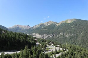 A mountainous landscape with a road leading to a building surrounded by dense forest.