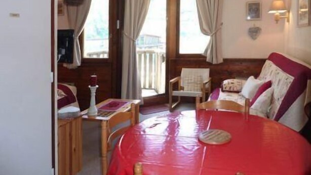 A cozy room with a bed, a small table, and a chair. There is a window with curtains, a wall-mounted light, and a picture frame. - Resort center, 9th floor, balcony, tv, ski locker, 32m², Les Orres (Les Orres)