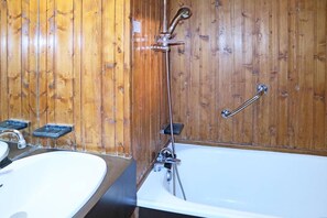 Ein Badezimmer mit Holzvertäfelung, einer Badewanne, einem Waschbecken und einer Dusche.