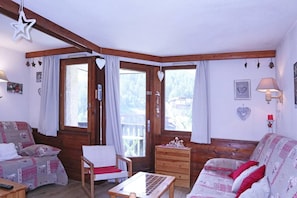 Una habitación acogedora con paredes de madera, una cama, una silla, una mesa y un aparador.