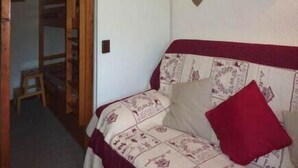 A bedroom with a bed, a wooden ladder, a small stool, and a wall-mounted clock. - Resort center, 9th floor, balcony, tv, ski locker, 32m², Les Orres (Les Orres)