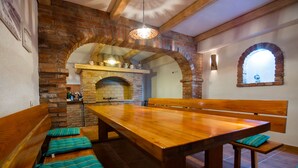 A rustic dining area with a wooden table and benches, brick arches, and a hanging light fixture. - JURIĆ apartments with outdoor pool and bargain in RAB-PALIT (Palit)