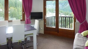 A room with a dining table, chairs, a television, and a sofa. - Ski-in/ski-out & foot of the slopes, 1st floor, balcony, tv, ski locker, 38m², Les Orres (Les Orres)