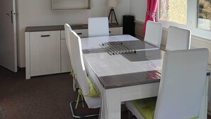 A dining area with a table, chairs, a clock, a shelf with decorative items, and a window with curtains. - Ski-in/ski-out & foot of the slopes, 1st floor, balcony, tv, ski locker, 38m², Les Orres (Les Orres)