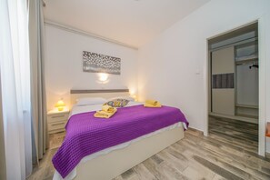 A bedroom with a bed, a nightstand, a wall-mounted light, and a closet. - Apt Lemon - Beautiful house in green with outdoor pool and barbecue area (Palit)