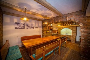 A rustic kitchen with a wooden table and bench, brick walls, and a brick oven. - Apt Lemon - Beautiful house in green with outdoor pool and barbecue area (Palit)