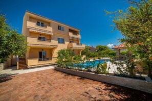 A multi-story building with balconies, a swimming pool, and surrounding greenery. - Apt Lemon - Beautiful house in green with outdoor pool and barbecue area (Palit)