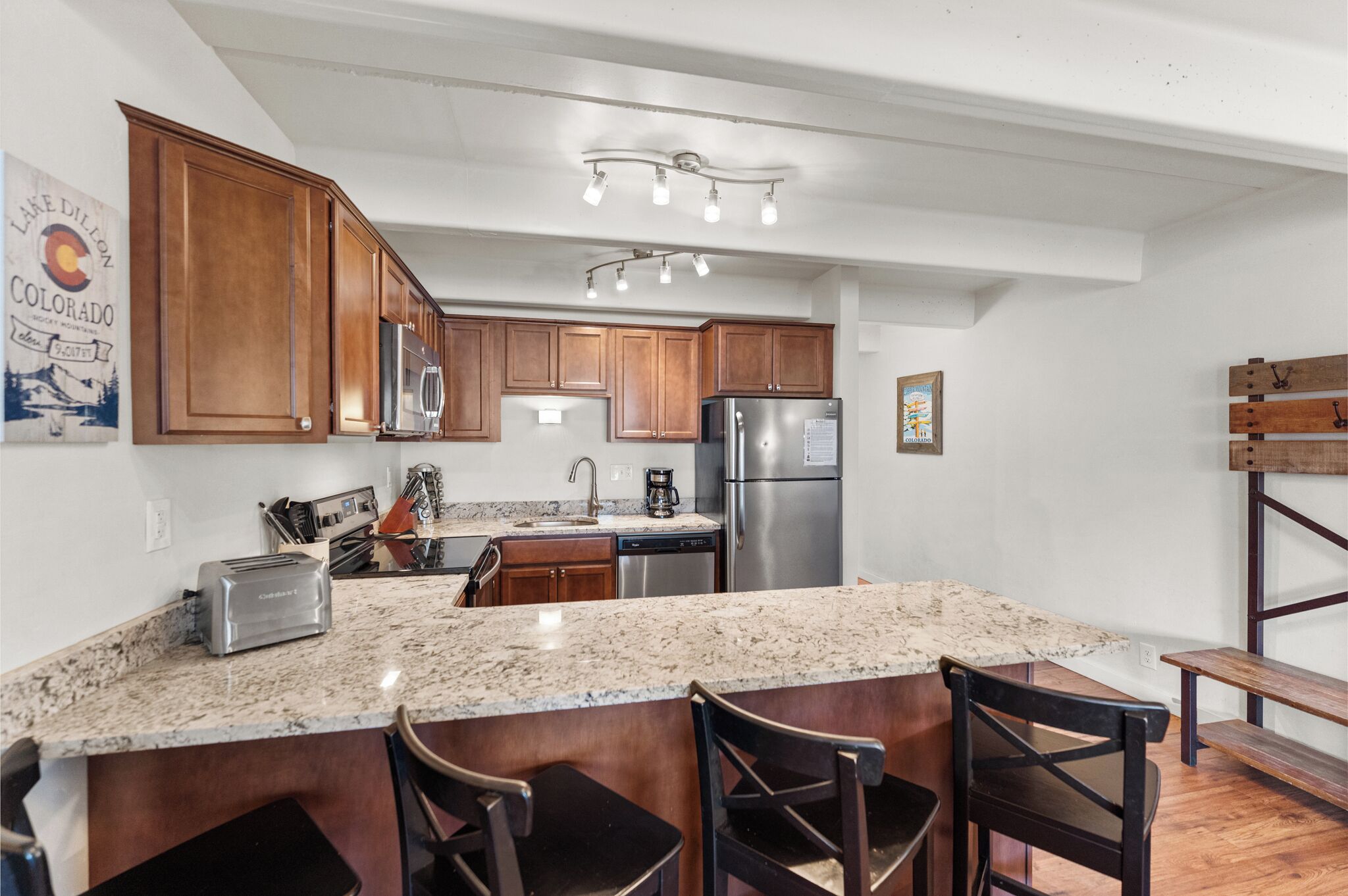 A modern kitchen with wooden cabinets, a granite countertop, and stainless steel appliances.