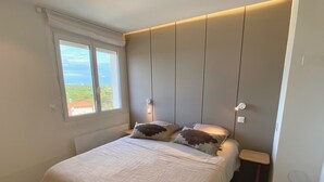 A bedroom with a bed, two bedside tables, a window, and a view of greenery outside. - Superb view of the ocean, the beach at your feet! (Soorts-Hossegor)