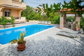 Una piscina con sillas de descanso y un patio amoblado.