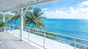 A covered balcony with a view of the ocean and palm trees. - Villa Leynita Bay, 5 bedrooms, sleeps 12 on the beach of Diamant Martinique  (le diamant)
