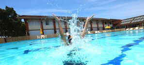 A swimming pool with a person diving into the water, surrounded by sun loungers and a building with a tiled roof. - Pousada Pontal de Guaratuba (Guaratuba)