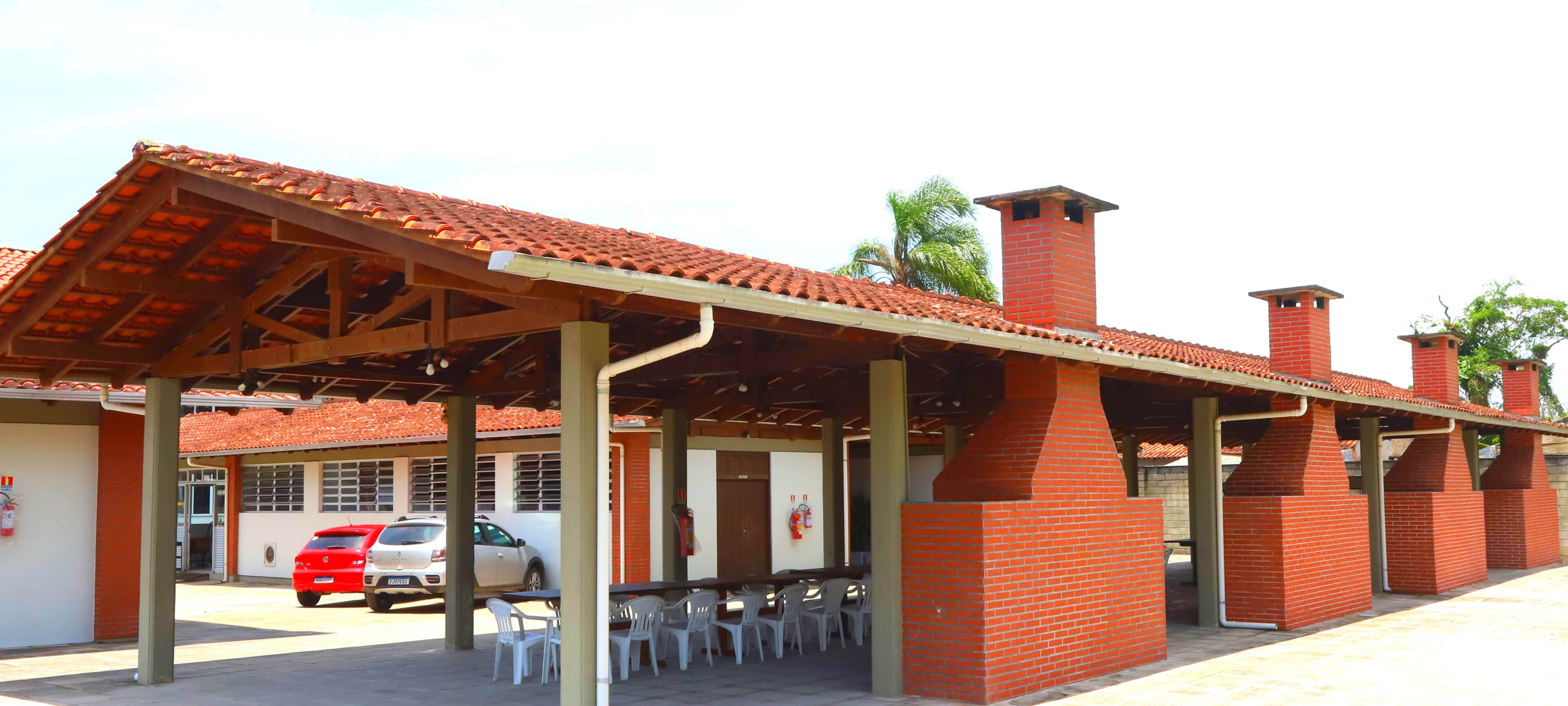 A covered outdoor seating area with brick chimneys, a fire extinguisher, and a parked car.
