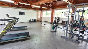 Une salle de sport équipée de tapis de course, d’appareils de musculation et de ballons d’exercice.