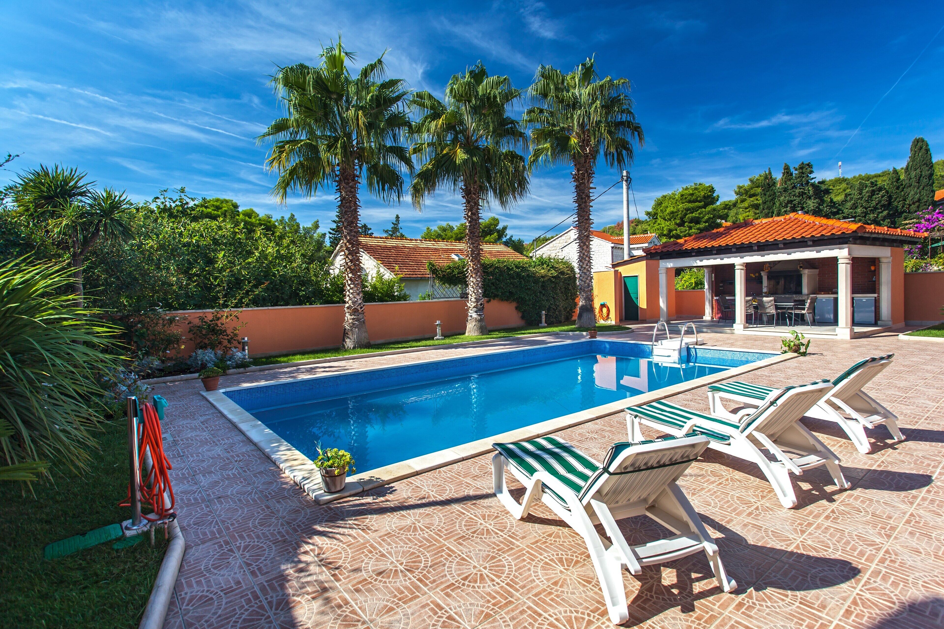 Piscina com espreguiçadeiras e palmeiras.