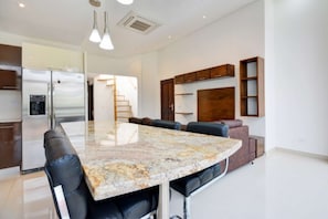 A modern kitchen with a large island, stainless steel appliances, and wooden cabinetry.