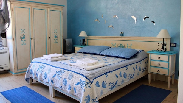 Un dormitorio con cama, dos mesitas de noche, un armario y una pared decorada con diseños de pájaros.