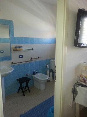 A bathroom with a sink, bidet, and toilet. There is a small table and a mirror above the sink. - Sabbia e Mare (Porto Torres)