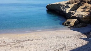 Un paisaje costero con agua azul cristalina, acantilados rocosos y una playa arenosa.