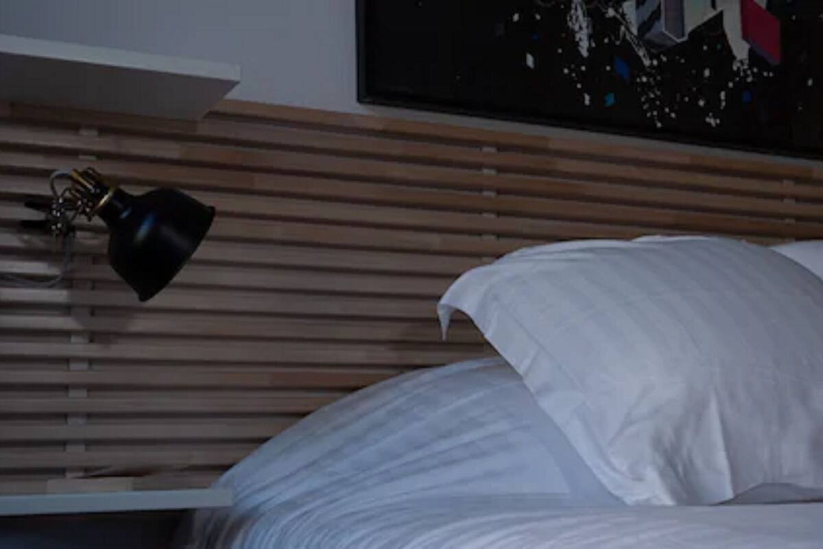 A bed with white sheets and a wooden headboard.