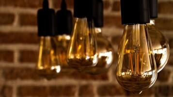 A close-up of several hanging light bulbs with a brick wall background.