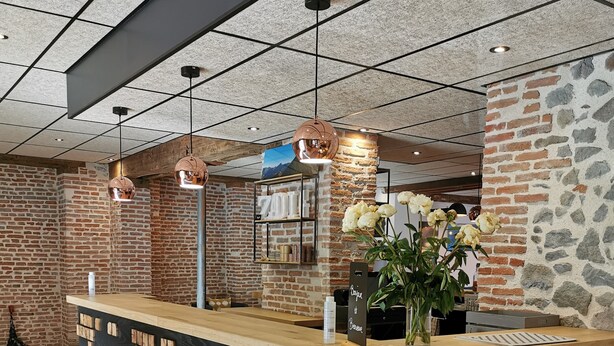 Zona de bar con suelo a cuadros, pared de ladrillo y mostrador de madera.