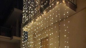 A building facade adorned with string lights, a gated entrance, and a small garden area.