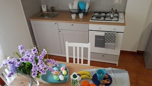 A kitchen with a sink, stove, and oven. There is a dining table with a vase of flowers, a plate with Easter eggs, and a carton of milk.