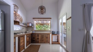 Une cuisine moderne avec des meubles en bois, un four à micro-ondes encastré et une grande fenêtre donnant sur un paysage verdoyant.