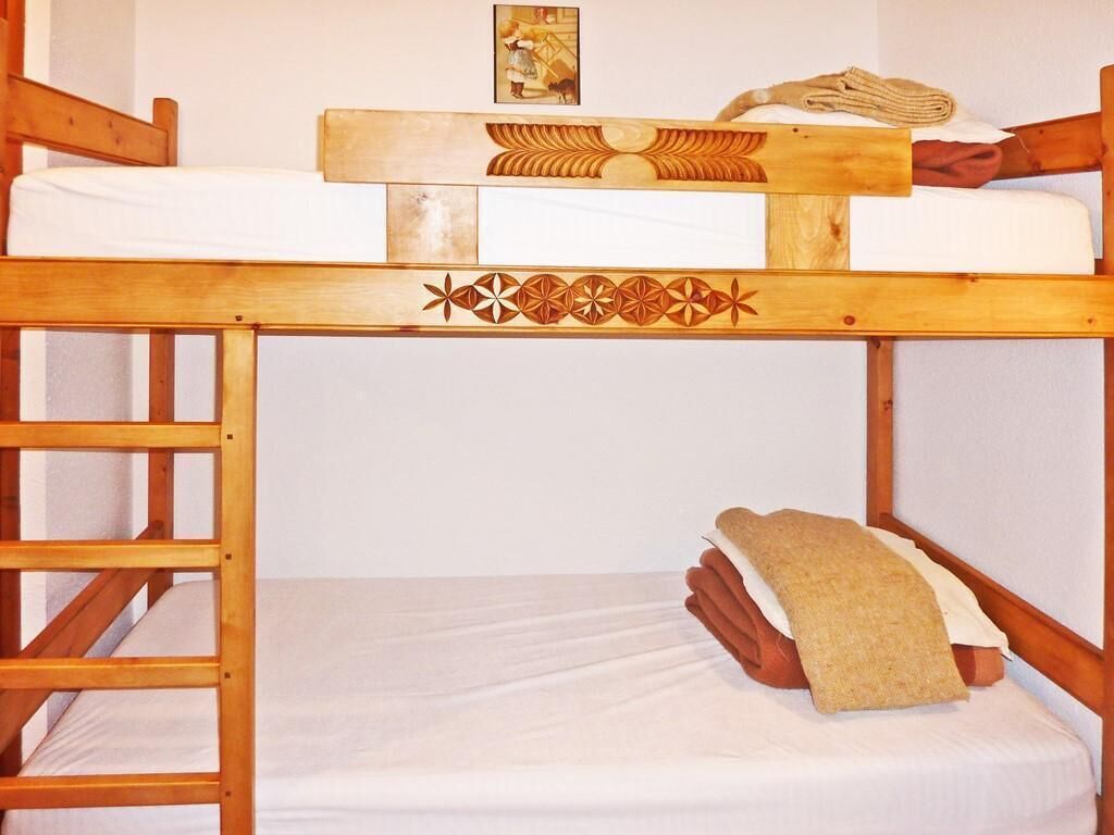 A bunk bed with a decorative headboard, a small picture on the wall, and a rolled-up towel on the lower bunk.