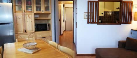 Ein gemütlicher Wohnbereich mit Esstisch aus Holz, einer Mikrowelle und einem Kühlschrank.