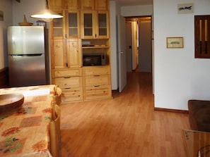 A kitchen with wooden cabinets, a refrigerator, a microwave, and a dining table with chairs.