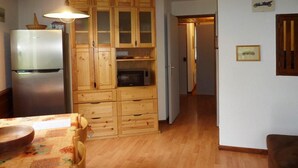 Keittiössä on puukehikoiset kaapit, jääkaappi, mikroaaltouuni sekä ruokapöytä tuoleineen.