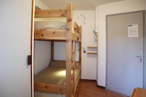 A bunk bed room with a door and a small shelf.