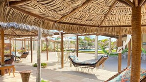 A covered outdoor seating area with wicker furniture and a thatched roof. - Pousada Jardins do Mar (Cascavel)