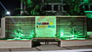 A bench in front of a wall with a sign that reads "POR AMOR A AGUAS BELAS". - Pousada Jardins do Mar (Cascavel)