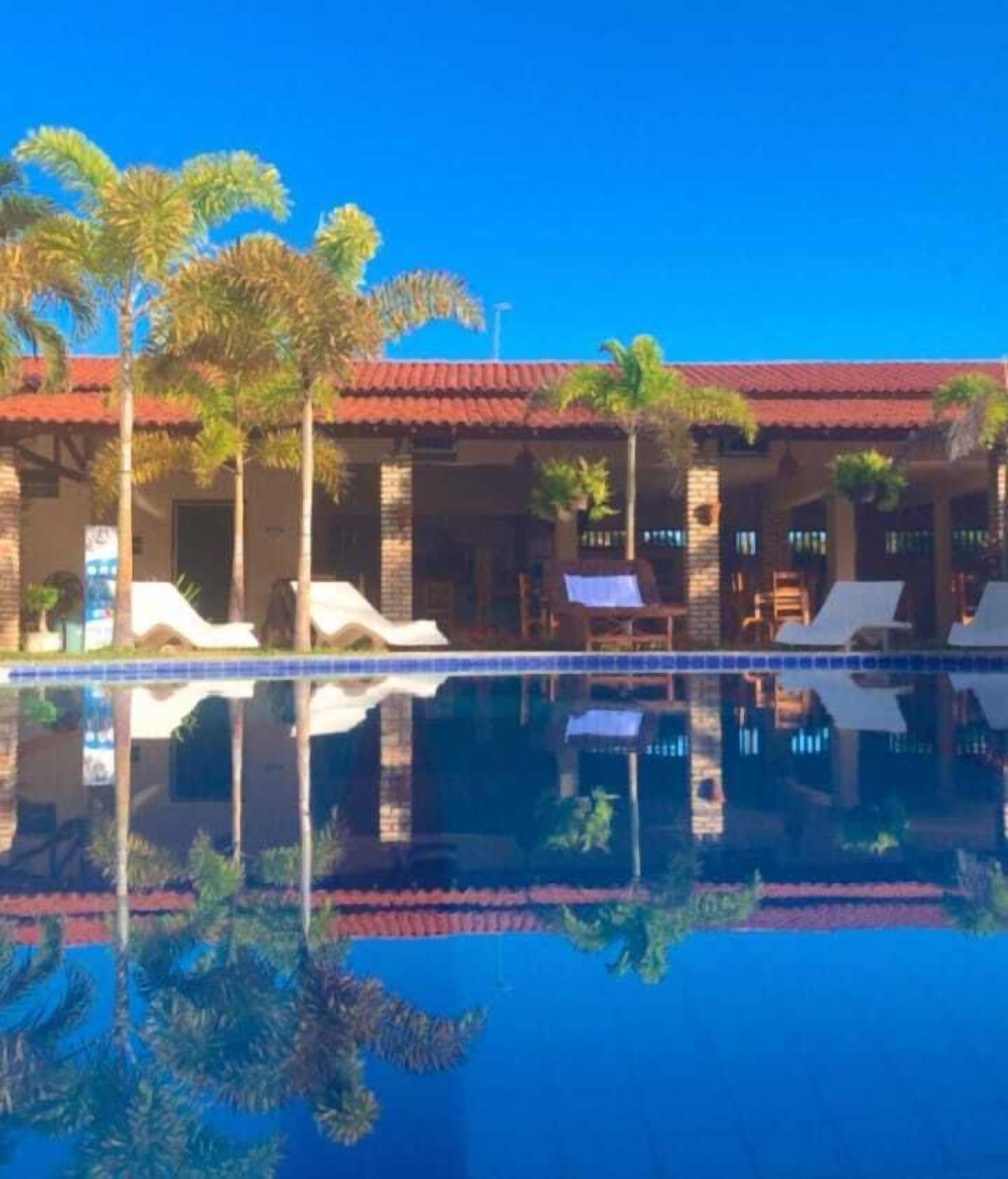 A resort with a swimming pool, lounge chairs, and palm trees.