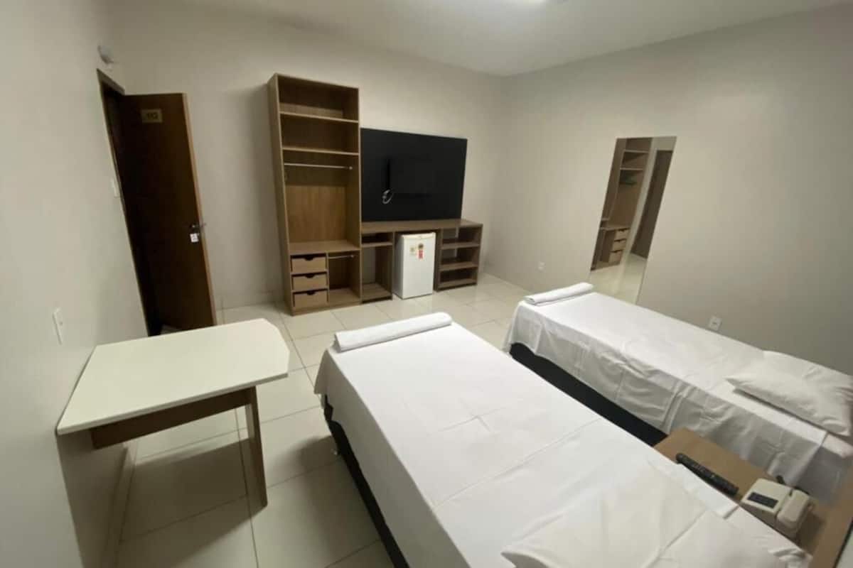 Una habitación con dos camas individuales, un escritorio, un armario y una televisión.