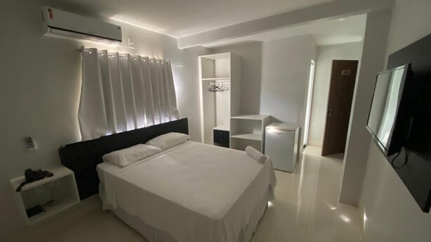 A modern bedroom with a large bed, a bedside table, a wardrobe, and a TV.