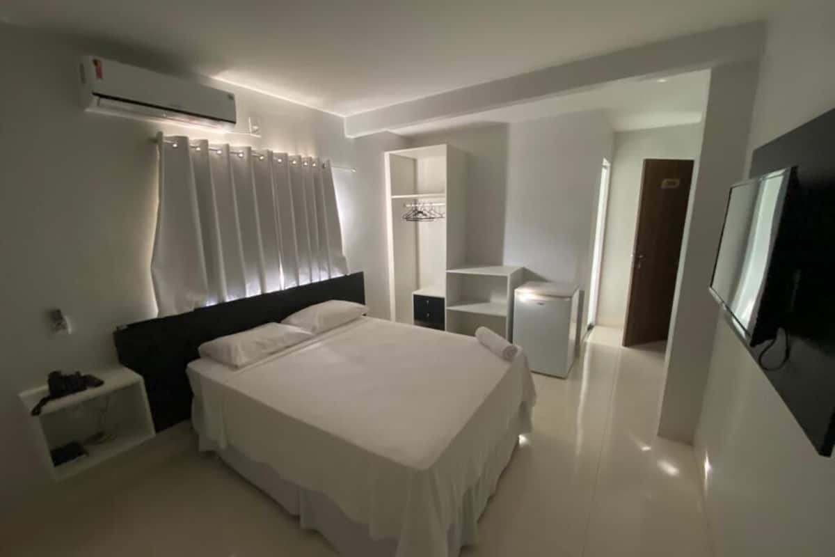Un dormitorio moderno con una cama grande, una mesita de noche, un armario y un televisor.