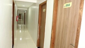 A hotel corridor with wooden doors, each marked with a number.