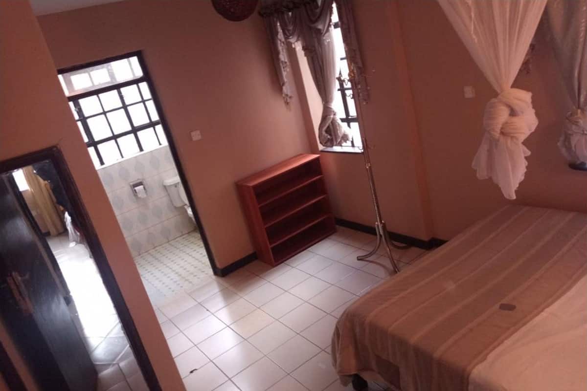 A bedroom with a bed, a window, a wardrobe, and a standing lamp.