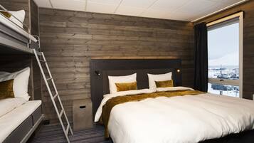 A hotel room with a bunk bed, a large bed, a wooden wall, a window with a view, and a ladder.